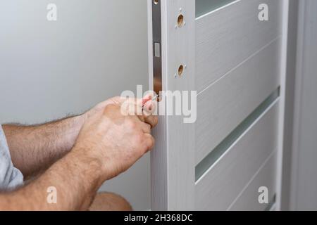 Photo of male hands, with screwdriver, tightening door hinge Stock Photo