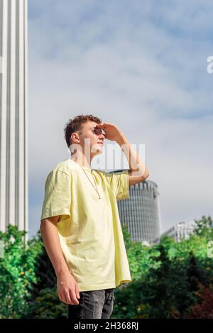 Young man in yellow T-shirt looking at the horizon with his hand on his forehead Stock Photo