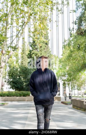 Young man walking down the street wearing black sweatshirt and hoodie Stock Photo