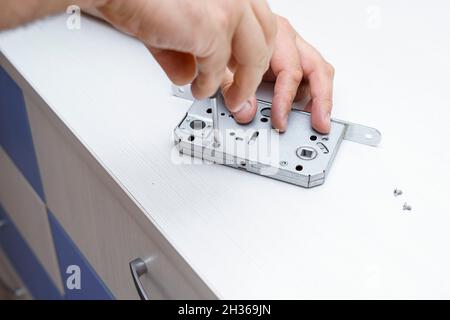 the master disassembles the door lock with a screwdriver. Stock Photo