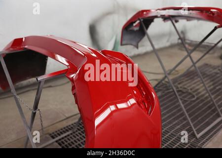 Painted red bumpers to drying in workshop closeup. Auto detailing concept Stock Photo