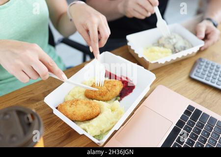 Staff eating cutlets with mashed potatoes from cardboard boxes in office closeup Stock Photo
