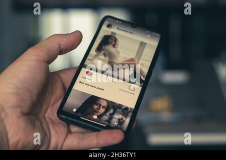 dependence on social networks concept. man looks through a news feed on a social network and puts likes in new posts of girls. All the graphics on the Stock Photo