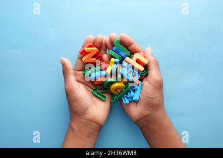 colorful plastic letters on child's hand on blue background  Stock Photo