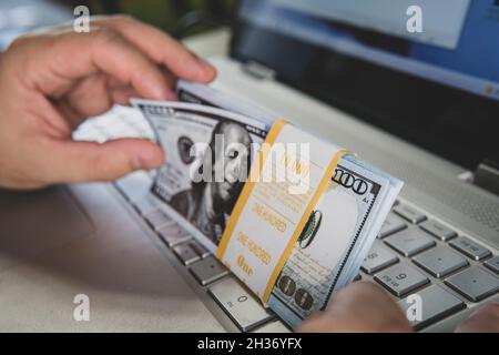 Laptop and US dollar ,Computer notebook and dollar banknotes on a wooden background, Technology with US dollar bank note, earning money on the Interne Stock Photo