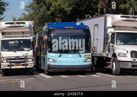 TRAFFIC JAM. A new York City bus squeezes through a tight spot on Lee Ave. in Williamsburg, Brooklyn, New York City Stock Photo