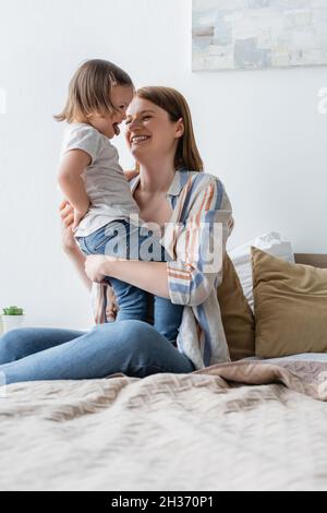 Happy woman looking at daughter with down syndrome sticking out tongue Stock Photo