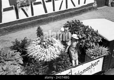 Zwei kleine Mädchen auf dem firmeneigenen Festwagen des Rettich Versands Honacker beim Festumzug zum Rettichfest in Schifferstadt, Deutschland 1930er Jahre. Parade float of the radish dispatch company Honacker with a staff member and two little girls at the pageant of the annual radish fair at Schifferstadt, Germany 1930s. Stock Photo