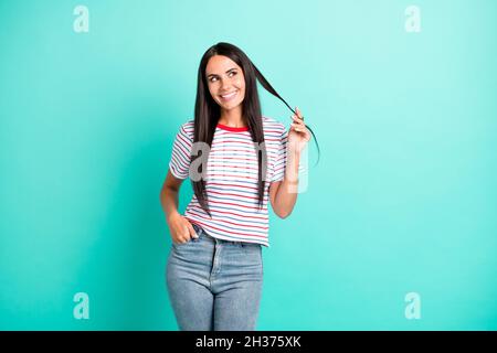 Photo of charming cheerful person hand finger play with hair look empty space isolated on teal color background Stock Photo