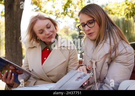 Two mature female friends studying together in the park, reading books Stock Photo
