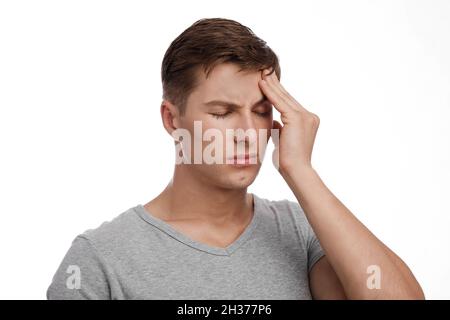 Despaired sad attractive young caucasian guy suffering from headache, touching forehead, isolated on white background Stock Photo