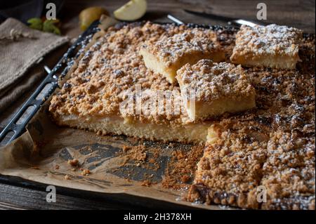 Rustic apple cake with crumbles on a baking sheet served on wooden table. Stock Photo