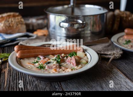 Rustic dinner or lunch table with a homemade fresh cooked white bean soup and vienna sausages. Served with bread Stock Photo
