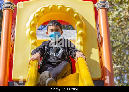 Masked boy in the park. Brunette boy in black hoodie and blue mask plays in the park. Front view. Selective focus Stock Photo