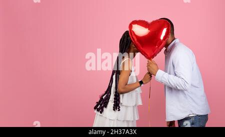 African american couple kissing and hiding behind red heart Stock Photo ...