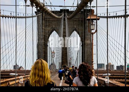 NEW YORK, NY, USA - APRIL 27, 201: Tourist walking on busy Brooklyn bridge on Manhattan. Stock Photo