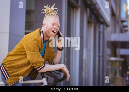 Happy albino african american man with dreadlocks talking on smartphone Stock Photo
