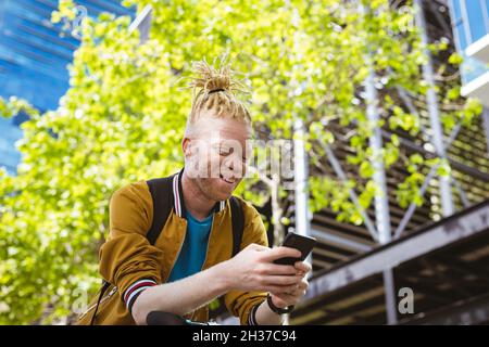 Happy albino african american man with dreadlocks using smartphone Stock Photo