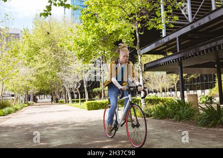 Thoughtful albino african american man with dreadlocks riding bike Stock Photo