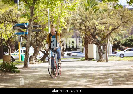 Thoughtful albino african american man with dreadlocks riding bike Stock Photo