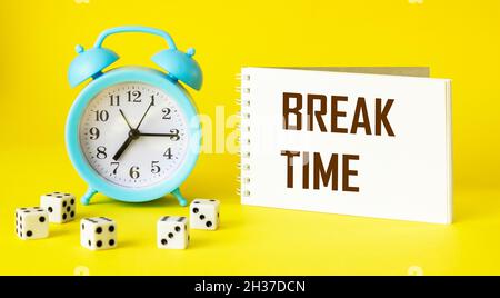 Notepad with the words Time Break on a yellow background with a clock. Stock Photo