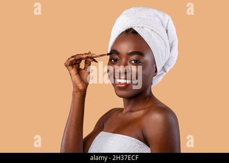 Portrait of smiling woman applying mascara on brows Stock Photo