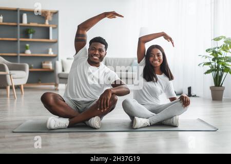 Young black couple doing side bend exercise together Stock Photo