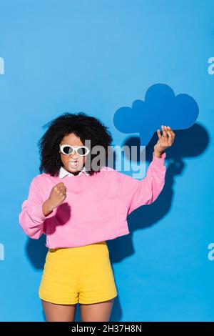 irritated african american woman with blank thought bubble showing fist on blue Stock Photo