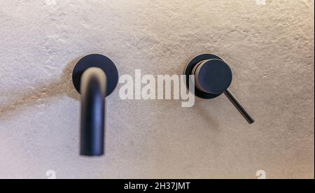 Modern washbasin black color round taps mounted on grey tiled wall. Modern bathroom interior detail, sink basin faucets, minimalist design, front view Stock Photo