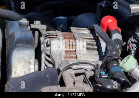Alternator. Dusty details of a flat-four (boxer) car engine compartment under the open hood. Closeup side view Stock Photo