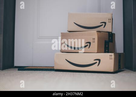 Boxes with Amazon logo in front of the house door. Order on delivery. Christmas gifts in cardboard box on the doormat. Amazon Prime priority delivery. Stock Photo