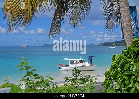 Small fishing boat anchored before Paradise Beach on Carriacou, island of the Grenadine Islands, Grenada in the Caribbean Sea Stock Photo