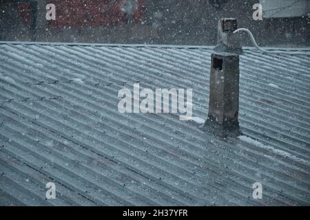 Roof of house made of metal panels. Corrosion exists on roof and old style chimney stack during overcast weather and heavy rainy day Stock Photo