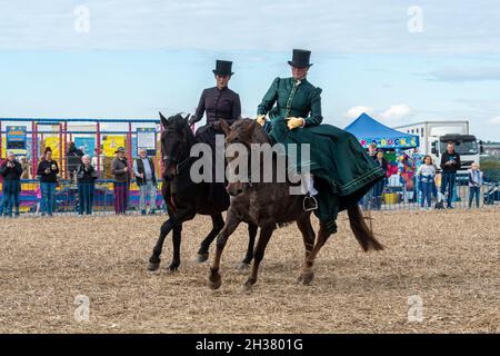 Two women in period costume doing a side-saddle horse-riding display at a horse event, UK Stock Photo