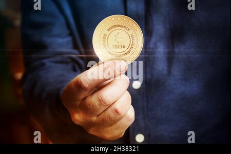 Theta Network cryptocurrency symbol golden coin in hand abstract concept. Stock Photo