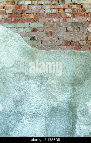 Gray plastered old brickwall with chipped stucco pieces. Grunge red and white brick wall with damaged surface background Stock Photo