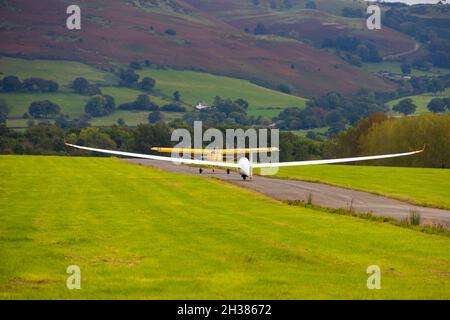 Schempp-Hirth Duo Discus glider launching by aerotow behind a yellow Eurofox tug. Lleweni Parc, Denbighshire, Wales. Stock Photo