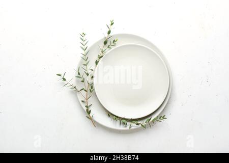 Plates and green eucalyptus branches on light background Stock Photo