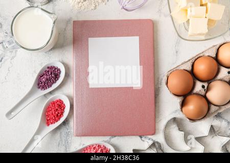 Recipe book with various ingredients and kitchen utensils on light background Stock Photo