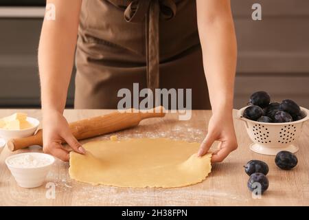 Woman preparing dough for plum galette at table Stock Photo