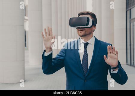 Surprised male office worker dressed formally stands outdoors in 3d goggles Stock Photo