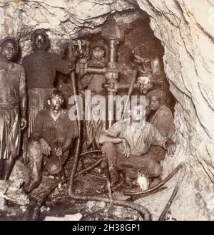 Machine driving, City & Suburban Gold Mine, Johannesburg, South Africa, about 1920, with black workers, a child and white foremen Stock Photo