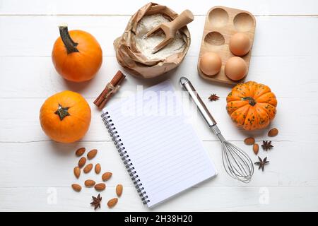 Composition with notebook and ingredients for preparing pumpkin pie on light wooden background Stock Photo