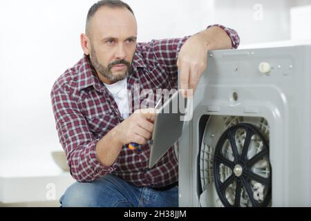 man using tablet to fix the washing machine Stock Photo