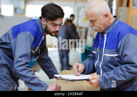 senior laborer in blue work wear with colleague Stock Photo