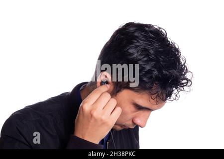 Man putting on headphones isolated on white background. Young latino guy using or putting on headphones to listen to music. Stock Photo
