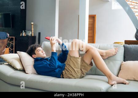 The boy playing online game on smartphone at home Stock Photo