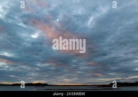 Clouds lit up at sunset over Whaleboat Island. Casco Bay.  Harpswell Neck, Maine. Stock Photo