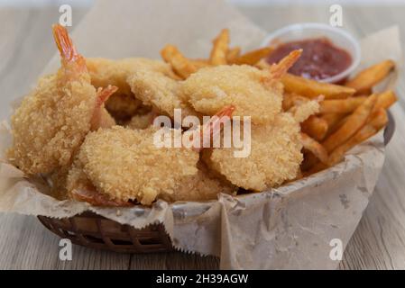 Basket of deep fried crispy shrimp served with french fries and a convenient dipping sauce. Stock Photo