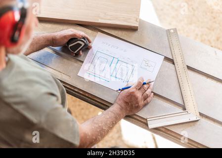 person drawing on wooden board with tape measure and ruler Stock Photo